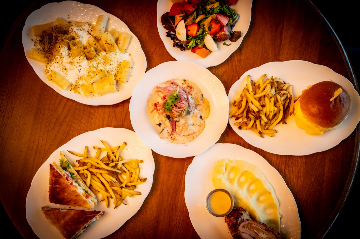Dishes at Les Causeurs seen from above, pasta, fries and salads